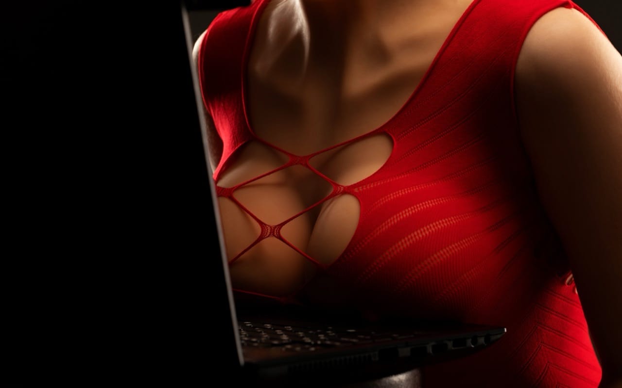Performer in red at a laptop against a dark background